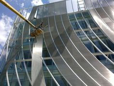 a man on a rope attached to the side of a tall building with glass windows