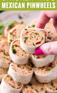 a hand is picking up some food from a platter that has several rolls on it