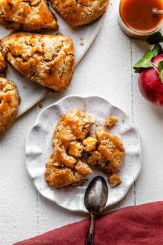 a white plate topped with scones next to an apple pie