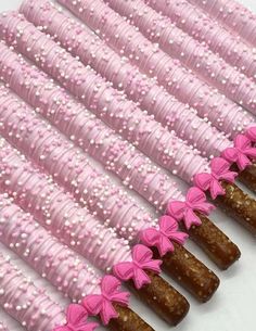 pink and white candy sticks are lined up in a row with bows on the ends