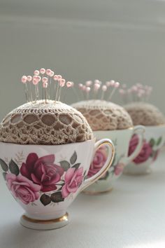 three teacups with pins in them sitting on a table