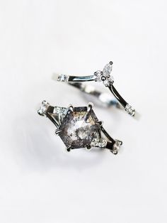 two silver rings with diamonds on them sitting next to each other in front of a white background