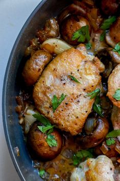 a pan filled with chicken and mushrooms covered in gravy, garnished with parsley