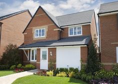 two story brick house with white garage doors and flowers in the front yard, on a sunny day