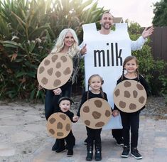 two adults and three children are dressed up as the same man and woman, holding cardboard signs that say milk