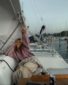 a woman sitting on the back of a sailboat with her arms up in the air