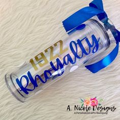 a personalized glass water bottle with blue ribbon and name printed on the side, sitting on a white furnishing