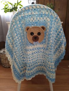 a crocheted teddy bear on a blue and white blanket sitting on top of a chair