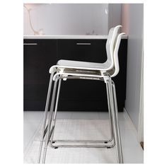 a white chair sitting on top of a kitchen floor next to a counter and cabinets