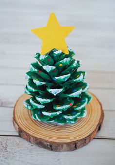 a pine cone christmas tree sitting on top of a wooden stump with a yellow star