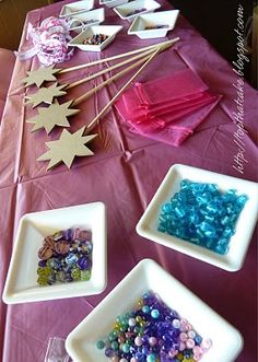 the table is set up with different types of beads and paper stars on it for decoration