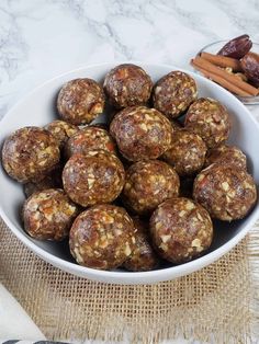 a white bowl filled with nuts next to cinnamon sticks