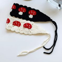 two crocheted headbands with red and white mushrooms on them next to a camera