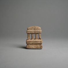 a small stone object sitting on top of a gray table next to a white wall