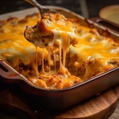 a casserole dish with cheese being lifted from the casserole pan by a fork