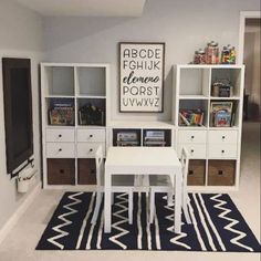 a white table sitting in front of a book shelf next to a blue and white rug