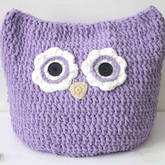 a knitted owl pillow with large eyes on it's face, sitting on a white surface