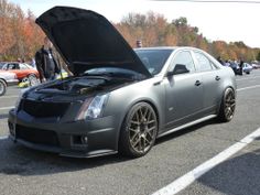 a gray car with its hood open on the side of the road next to other cars