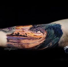 a man's arm with an ocean wave tattoo on it