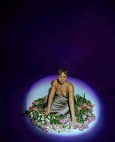 a woman is sitting in the middle of flowers