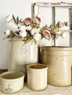 some white flowers are sitting in vases next to a mirror and an old window