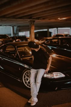 a man standing on the hood of a car in a parking lot with other cars