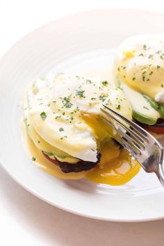 an open face sandwich on a plate with a fork sticking out of the egg and avocado