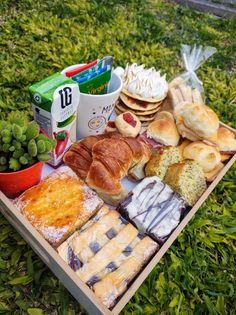 an assortment of breads and pastries on a picnic table in the grass,