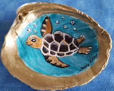 a painting of a sea turtle on a gold plate with bubbles in the water around it