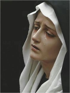 a woman wearing a white scarf and black hoodie with tears on her face as she stares into the distance