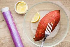 there is a potato on the plate with a fork in it and some lemons