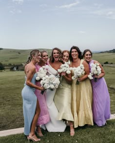 a group of women standing next to each other on top of a lush green field