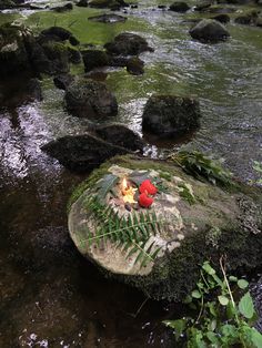 two candles sitting on top of a rock in the middle of a river