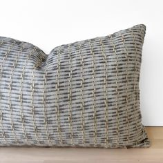 a gray and white striped pillow sitting on top of a wooden floor next to a wall