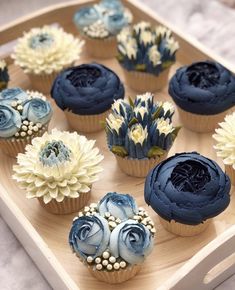 cupcakes decorated with blue frosting and flowers on a wooden platter, ready to be eaten