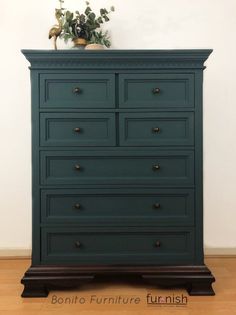 a green dresser sitting on top of a hard wood floor next to a white wall