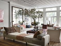 a living room filled with lots of furniture next to large windows on top of a hard wood floor