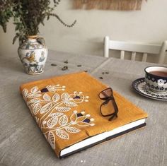 an open book sitting on top of a table next to a cup and saucer