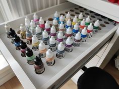 an open drawer with many different colored inks on it and a black chair next to it