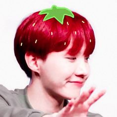 a boy with red hair wearing a green strawberry on his head