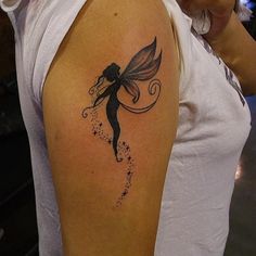 a woman with a tattoo on her arm is looking at the camera and has a small fairy