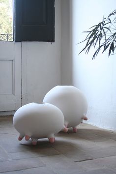 two white balls sitting on top of each other in front of a door with a plant