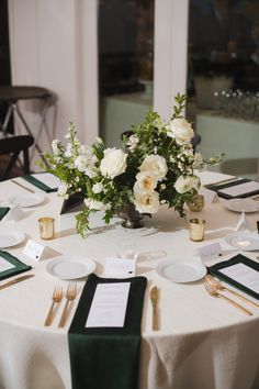 the table is set with white flowers and place settings for guests to sit down at