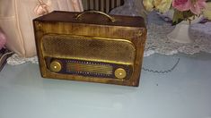 an old fashioned radio sitting on top of a table next to a purse and flowers