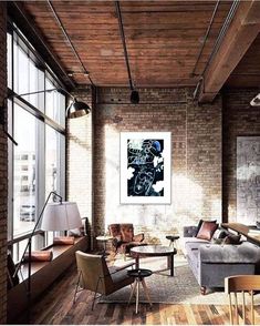 a living room filled with lots of furniture next to large windows and wooden flooring