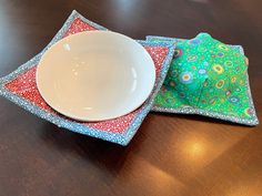 two placemats and a white bowl on a wooden table with a brown surface