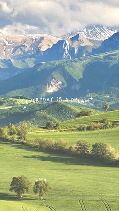 a green field with trees and mountains in the background that says every day is a dream