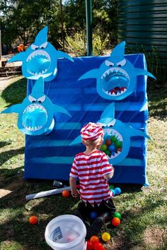 a young boy is playing in front of a shark play structure with balls and toys