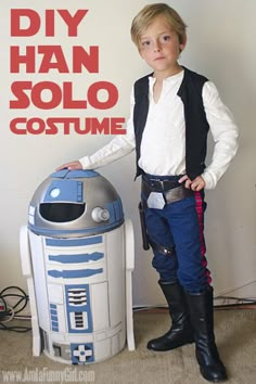 a young boy dressed in star wars costume standing next to a r2d2