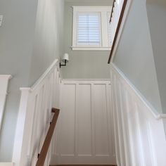 the stairs are painted white and have wooden handrails, along with a window above them